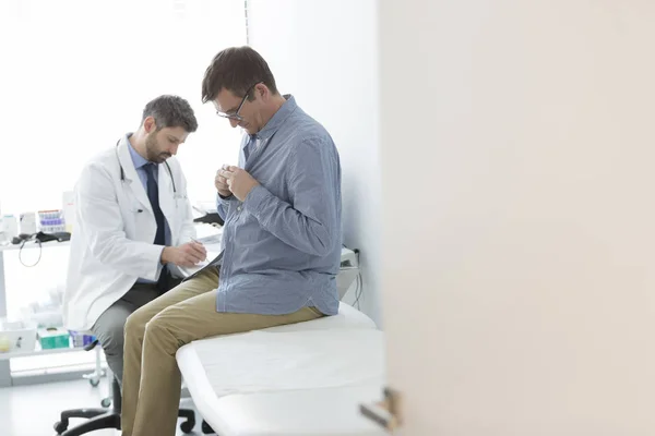 Arzt Liest Arztbericht Während Sich Patient Für Untersuchung Krankenhaus Auszieht — Stockfoto