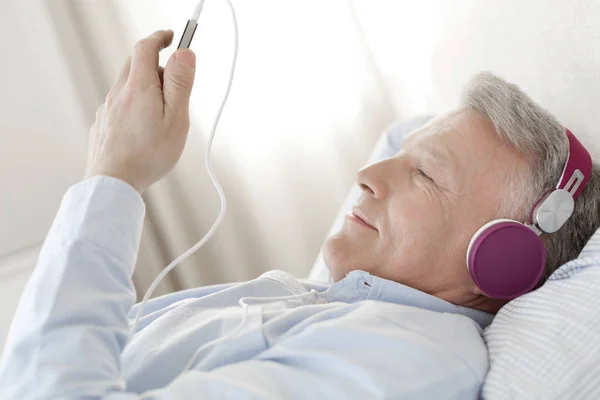 Dojrzały Człowiek Słuchania Muzyki Podczas Leżenia Sypialni Domu — Zdjęcie stockowe