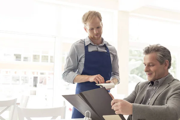 Young Waiter Standing Mature Customer Reading Menu Restaurant — Stock Photo, Image