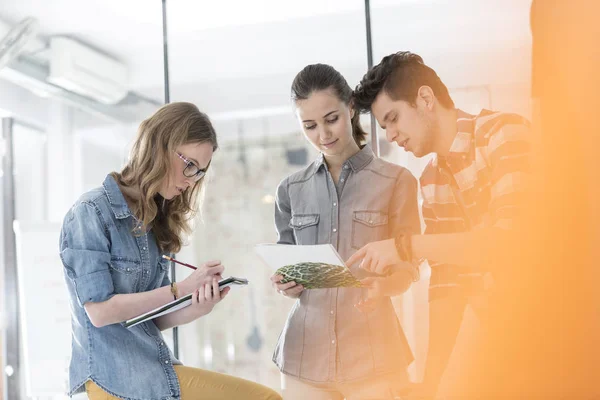 Business People Discussing Photographs While Colleague Writing Notes Office — Stock Photo, Image