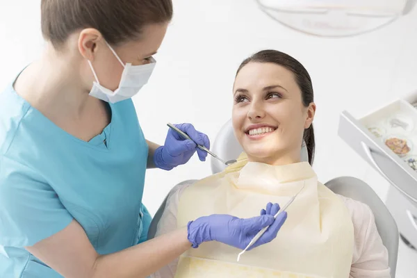女性歯科医診療所における歯科器械を若い患者見て笑顔 — ストック写真
