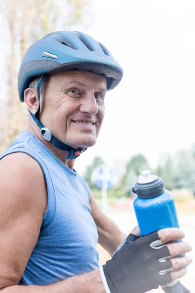 Portrét Usměvavá Starší Muž Nošení Cyklistické Přilby Zatímco Drží Láhev — Stock fotografie