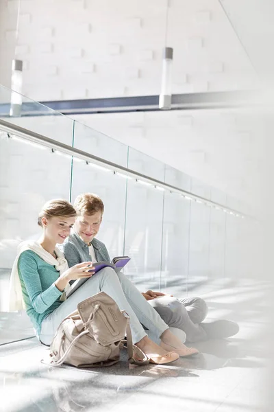 Amigos Sonrientes Leyendo Libro Mientras Están Sentados Pasillo Universidad —  Fotos de Stock