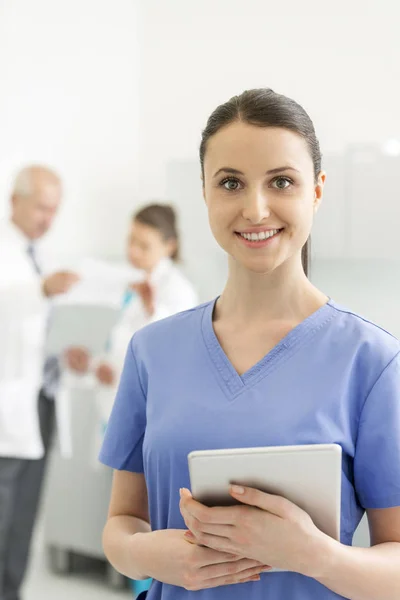 Lächelnde Krankenschwester Mit Digitalem Tablet Gegen Kollegen Klinik — Stockfoto