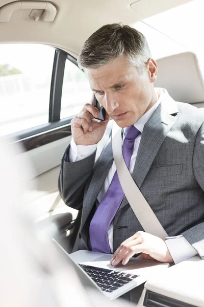 Executivo Usando Laptop Enquanto Fala Telefone Celular Carro — Fotografia de Stock