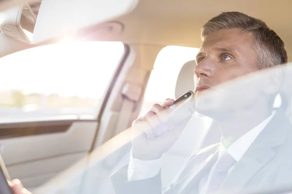 Businessman trimming while looking at mirror in car