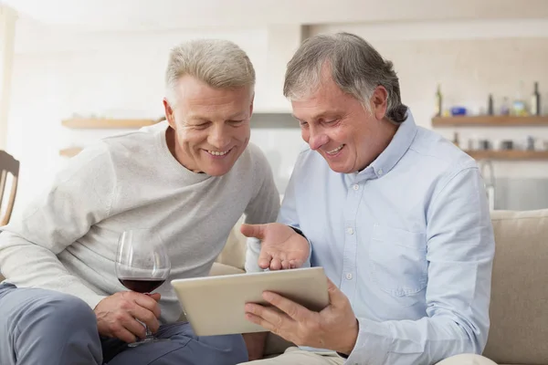 Sorrindo Homens Maduros Usando Tablet Digital Enquanto Sentados Casa — Fotografia de Stock