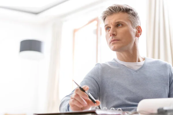 Thoughtful Mature Man Sitting Pen While Looking Away Apartment — Stock Photo, Image