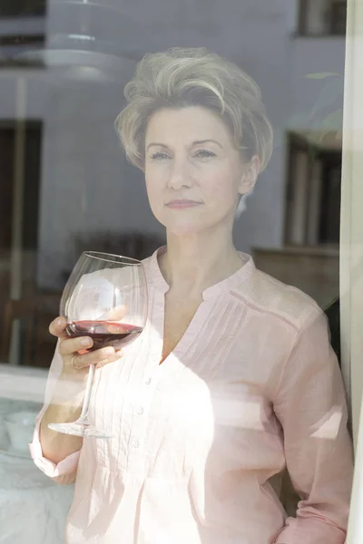 Thoughtful Mature Woman Holding Wineglass Seen Window — Stock Photo, Image