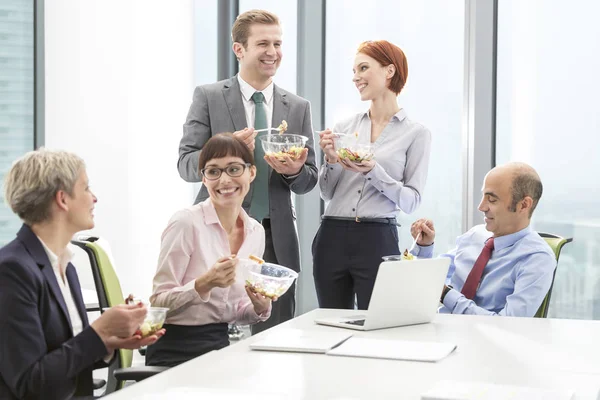 Uśmiechnięci Biznesowi Koledzy Jedzą Lunch Sali Konferencyjnej Podczas Spotkania Biurze — Zdjęcie stockowe