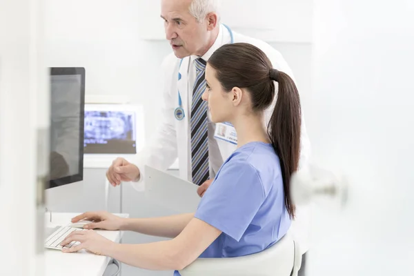 Enfermera Usando Ordenador Portátil Escritorio Mientras Médico Senior Explicar Clínica —  Fotos de Stock