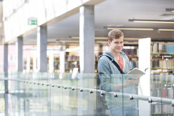 Retrato Homem Bonito Segurando Livro Enquanto Estava Corredor Contra Biblioteca — Fotografia de Stock