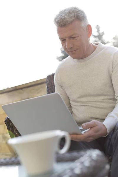 Ώριμος Άνθρωπος Χρησιμοποιώντας Φορητό Υπολογιστή Ενώ Κάθεται Στο Αίθριο — Φωτογραφία Αρχείου