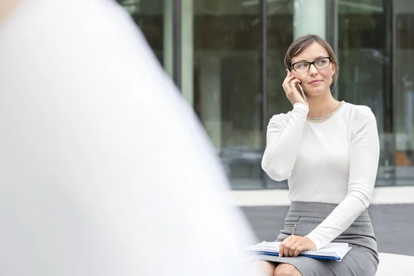 Ofis Binasına Karşı Otururken Akıllı Telefonda Konuşan Kendine Güvenen Kadını — Stok fotoğraf