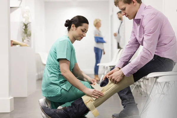 Медсестра Ассистирует Пациенту Ношении Коленного Корсета Больнице — стоковое фото