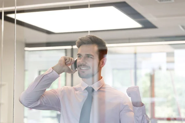 Glücklicher Geschäftsmann Der Büro Durchs Fenster Mit Dem Smartphone Spricht — Stockfoto