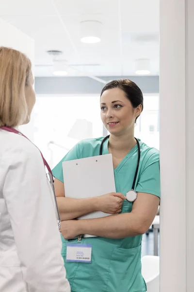 Krankenschwester Hält Klemmbrett Während Sie Mit Arzt Krankenhaus Diskutiert — Stockfoto