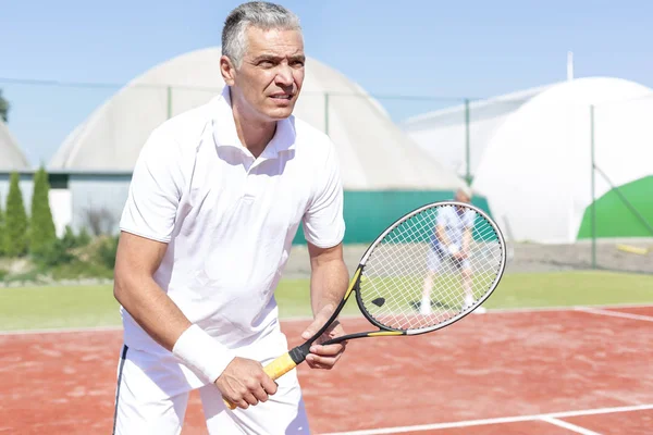 Zelfverzekerde Volwassen Man Permanent Met Tennisracket Tegen Vriend Spelen Dubbelspel — Stockfoto