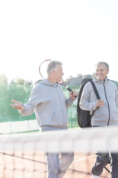 スポーツ衣料明確な青空のテニスコートで歩きながら話に笑顔の男性 — ストック写真