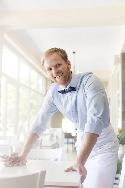 Portrait Smiling Confident Young Waiter Cleaning Table Restaurant — Stock Photo, Image