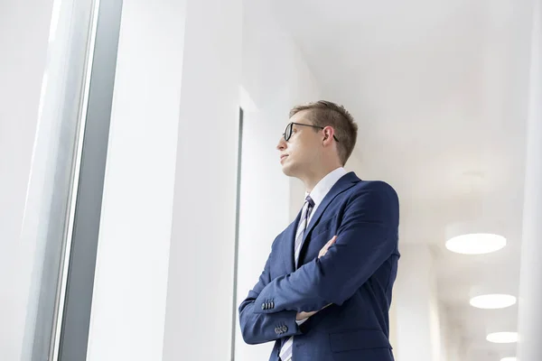 Young Thoughtful Businessman Standing Arms Crossed Office Corridor — Stock Photo, Image