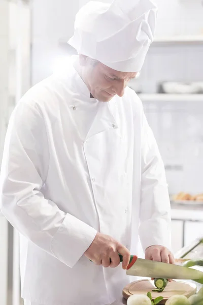 自信的厨师在餐厅厨房的船上切黄瓜 — 图库照片