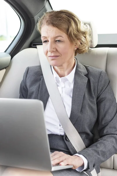 自信成熟的女商人在车上使用笔记本电脑 — 图库照片