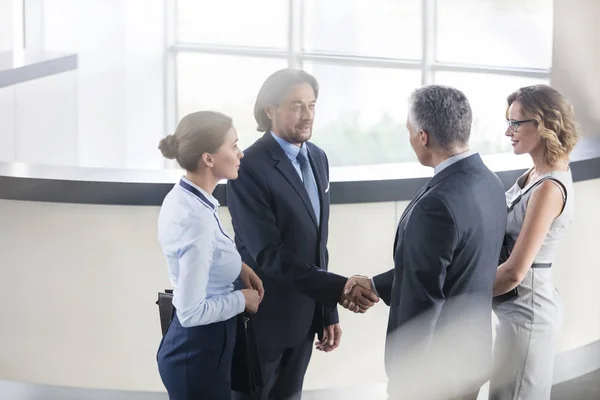 オフィスのレセプションで同僚と立ちながら挨拶するビジネスマン — ストック写真