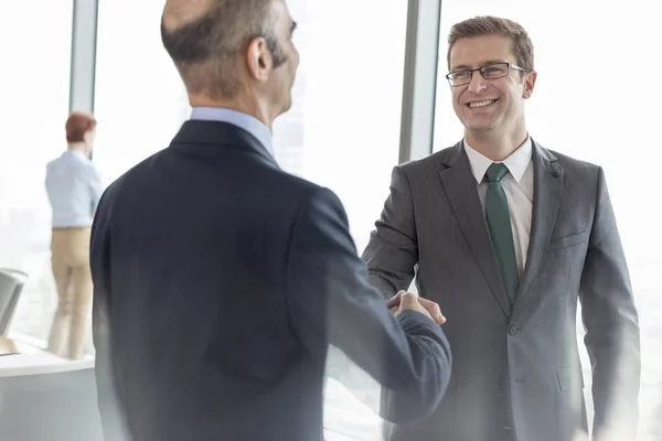 オフィスでの会議中に役員室で同僚と握手をする笑顔のビジネスマン — ストック写真