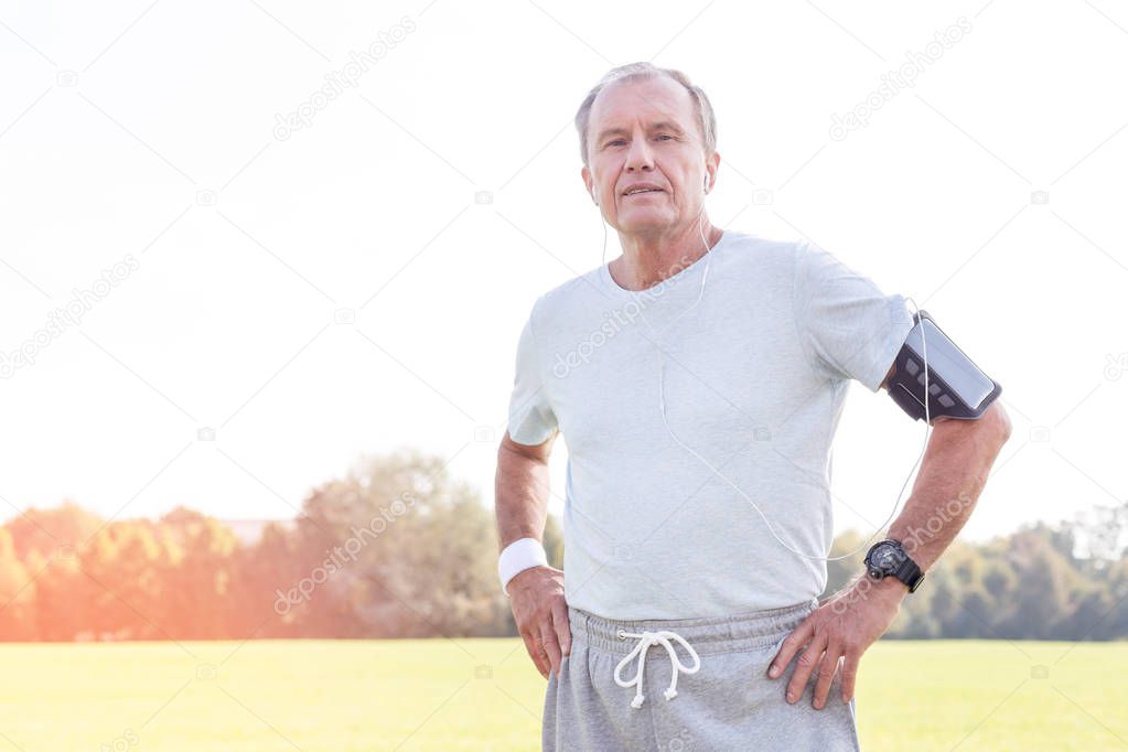 Confident senior jogger standing in park