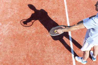 Olgun adam tenis topu kırmızı sahasında hizmet yüksek açılı görünüş
