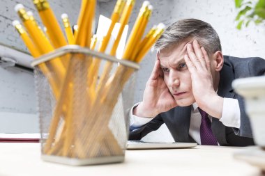 Ofiste masada dizüstü bilgisayar bakarak overworked olgun işadamı