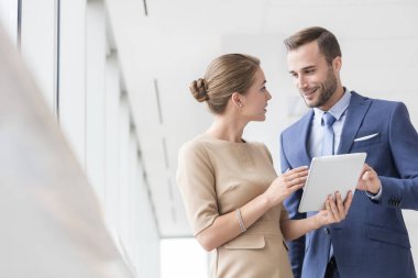 Kendine güvenen genç iş arkadaşları yeni ofiste dijital tablet üzerinden tartışıyor