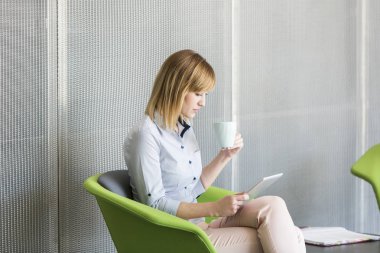 İş kadını ofiste kahve yaparken dijital tablet vasıl arıyorsunuz