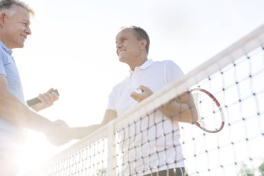 Erkekler tokalaşırken dururken, Tenis Kortu açık gökyüzü gülümseyen, düşük açılı görünüş