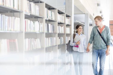 Kitaplığındaki kitap rafı tarafından yürürken elele çift