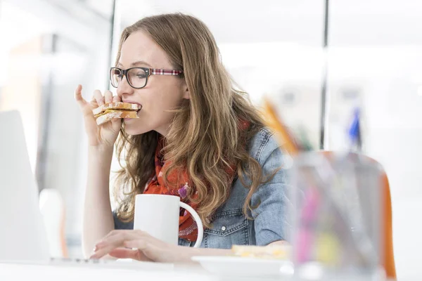 Donna Affari Affamata Mangiare Sandwich Durante Utilizzo Del Computer Portatile — Foto Stock