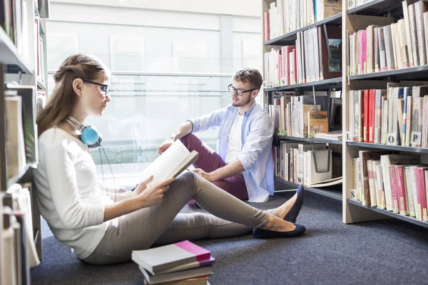 Estudiantes Leyendo Libro Mientras Están Sentados Contra Estanterías Biblioteca Universitaria —  Fotos de Stock