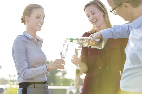 Sorrindo Jovem Empresário Derramando Vinho Duas Mulheres Negócios Festa Telhado — Fotografia de Stock