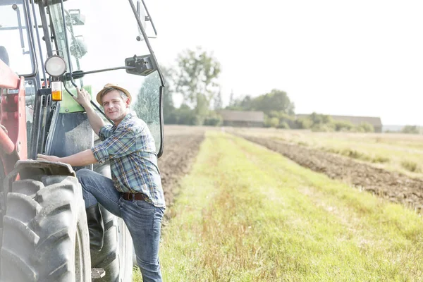 Kendine güvenen Çiftçi traktör çiftliğinde tırmanma portresi