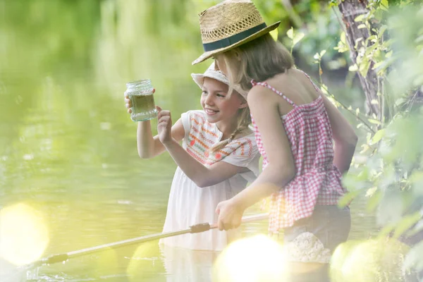站在湖里时 微笑的女孩向朋友展示罐子 — 图库照片