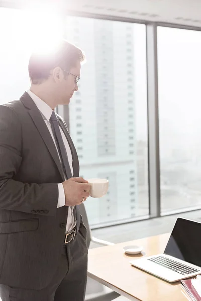 Zakenman Staande Met Koffie Kopje Kijken Naar Laptop Tafel Boardroom — Stockfoto