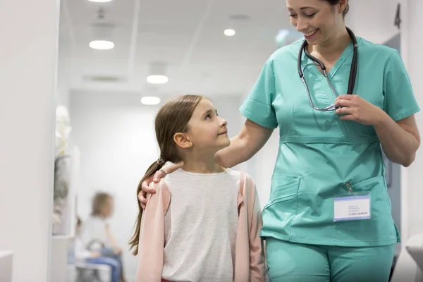 Chica Sonriente Mirando Enfermera Adulta Mientras Camina Pasillo Del Hospital —  Fotos de Stock