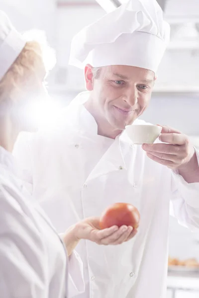 Chef Maduro Olhando Para Colega Trabalho Cheirando Comida Tigela Cozinha — Fotografia de Stock