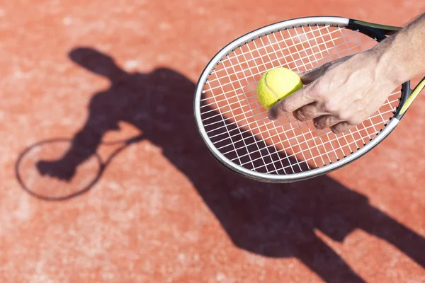 晴天在红球场上发球网球的成熟男子的手 — 图库照片