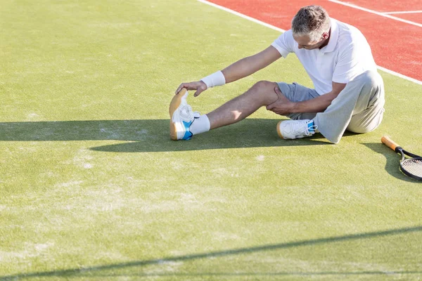 在网球场伸展运动中成熟男人热身的高视角 — 图库照片