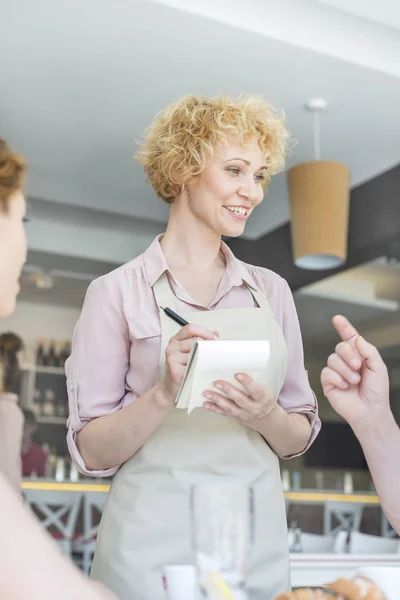 Uśmiechnięta Kelnerka Przy Zamówieniu Mężczyzny Siedzącego Restauracji — Zdjęcie stockowe