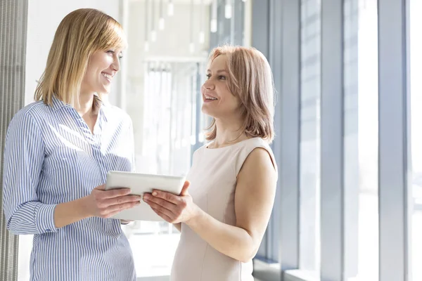 Mujeres Negocios Discutiendo Sobre Tableta Digital Corredor Oficina —  Fotos de Stock