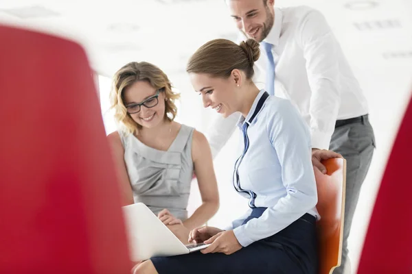 Smiling Businesswoman Using Laptop While Sitting Amidst Colleagues New Office — Stock Photo, Image