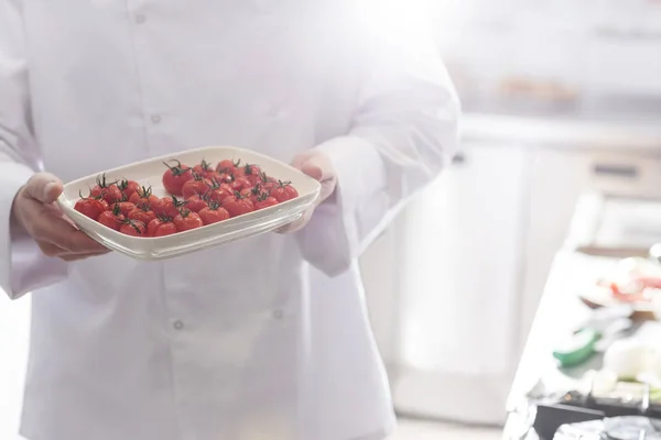 在餐厅的托盘里拿着新鲜樱桃西红柿的中段厨师 — 图库照片